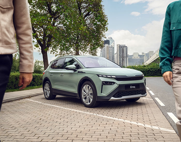 A couple walking away from a mint green Skoda