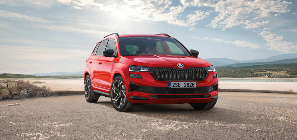 Front three-quarter shot of a red Karoq Sportline at the beach