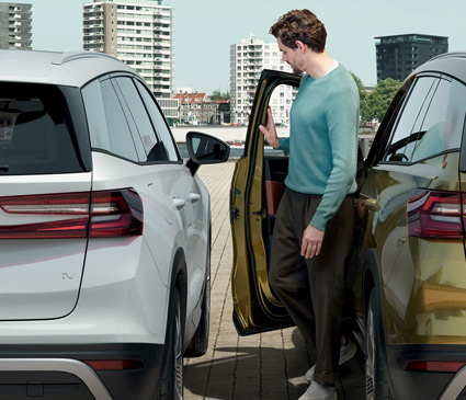 A man opening a car door next to another