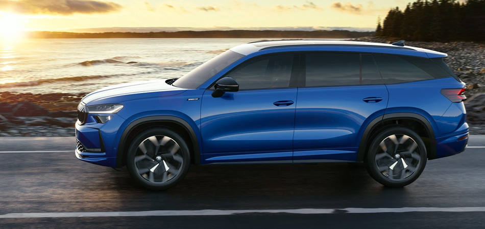 Side view of a blue SUV driving on a coastal road