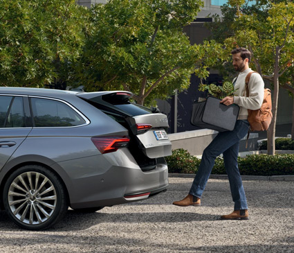 A man with full hands opening the boot to a Skoda with a foot gesture